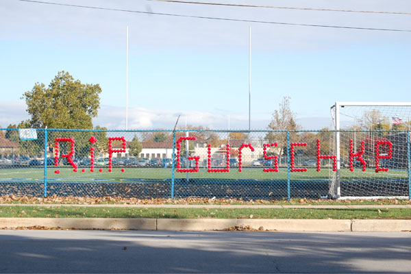 A memorial to Patrick Gurschke, spelled out in red plastic cups, graces the fence that runs along side the football field.