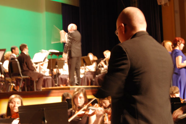 Fine Arts teacher James Baum directs in the foreground while retired and now part-time Fine Arts teacher Kevin McOlgan directs on the main stage for the Winter Holiday Concert.