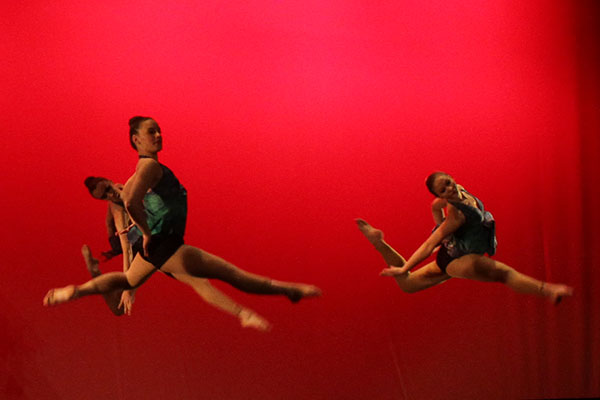 During the finale performance, junior Nicole LaBelle, sophomore Maddie Ackerman, and sophomore Rachel Bakalich leap into the air mid performance. 