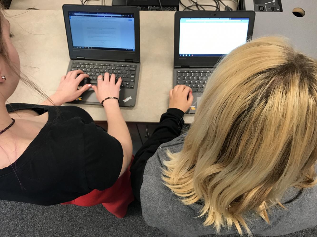 Two students using their personal chromebook in class. 
