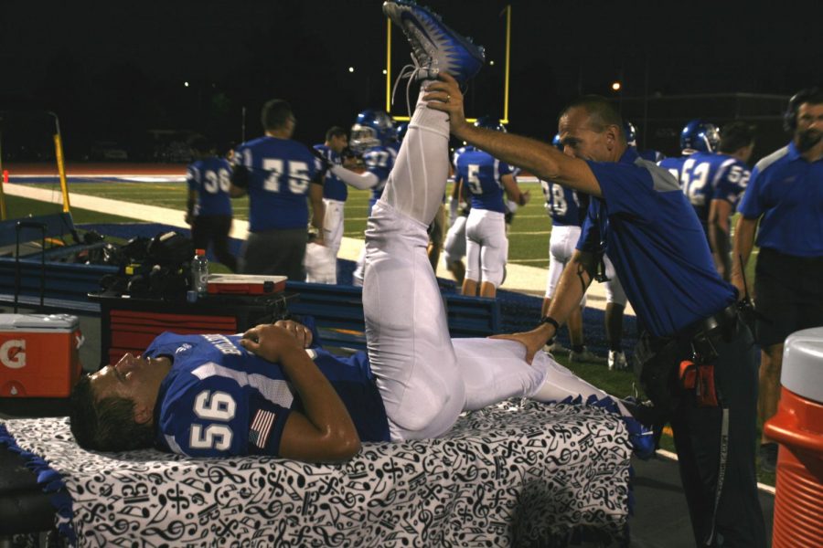 Trainer William Frye stretching a player's leg