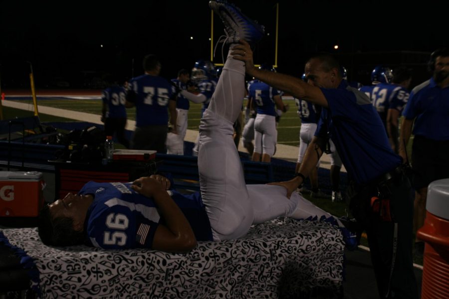 Varsity player getting his leg stretched by RB Trainer William Frye