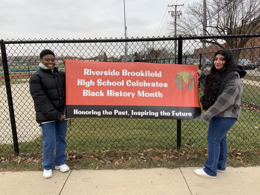 Shalah Russell and Miranda Bucio hanging up a sign for Black History Month.