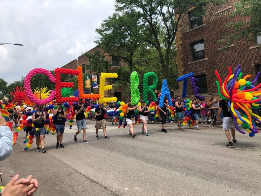 People holding up balloons at the pride parade.