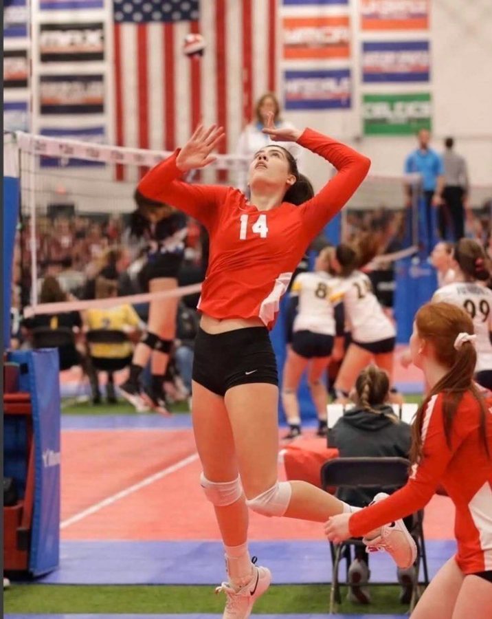 Colette Barnes spiking the ball during a game for her club volleyball team.