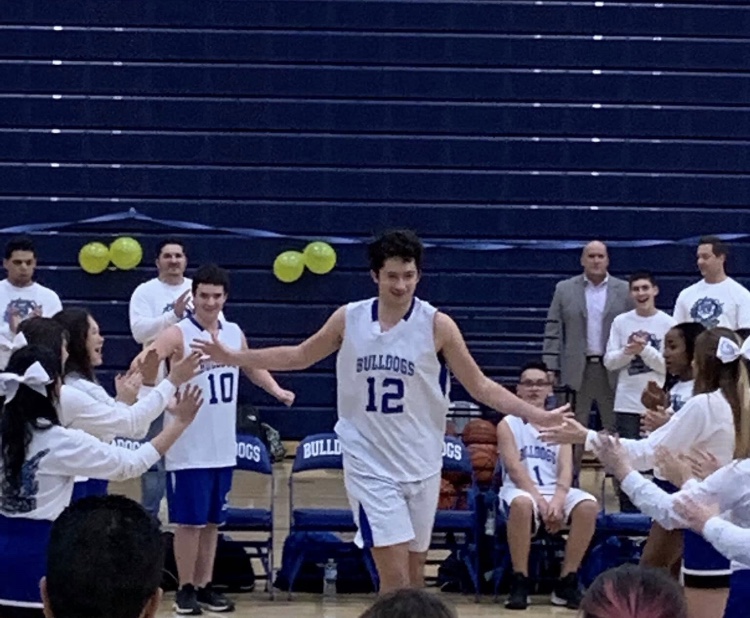 Trent Oltrogge running onto the court at the start of a special olympics basketball game.