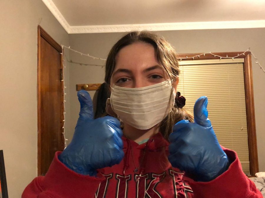 Mia posing after beating COVID-19 wearing gloves and a mask.