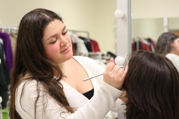 Vittoria Gentile applying makeup for an actor backstage.